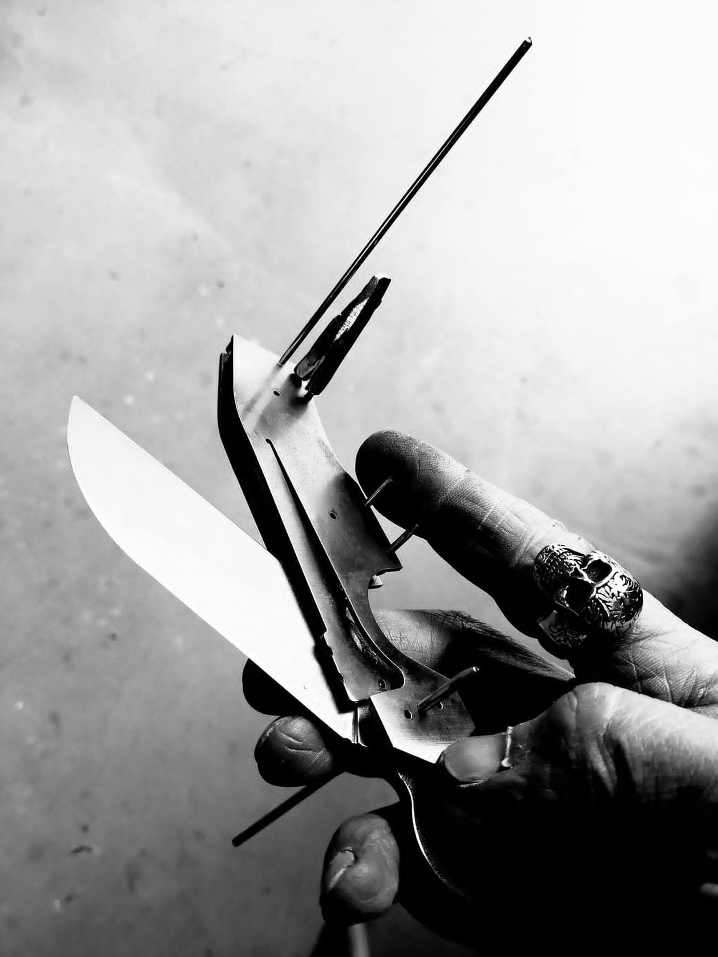 Couteau en cours de montage tenu en main, platines et axes apparents