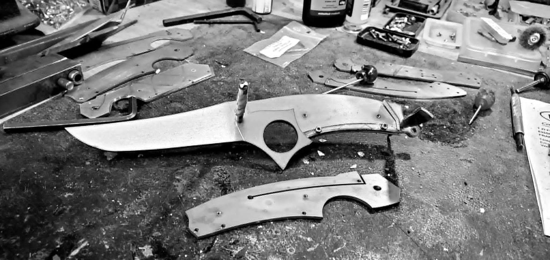 Atelier de coutellerie à Thiers : établi, limes et lame en cours de montage sous une lumière chaude.